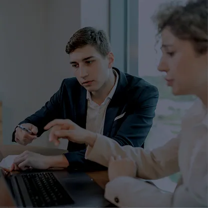 Deux personnes en train de discuter en regardant un ordinateur
