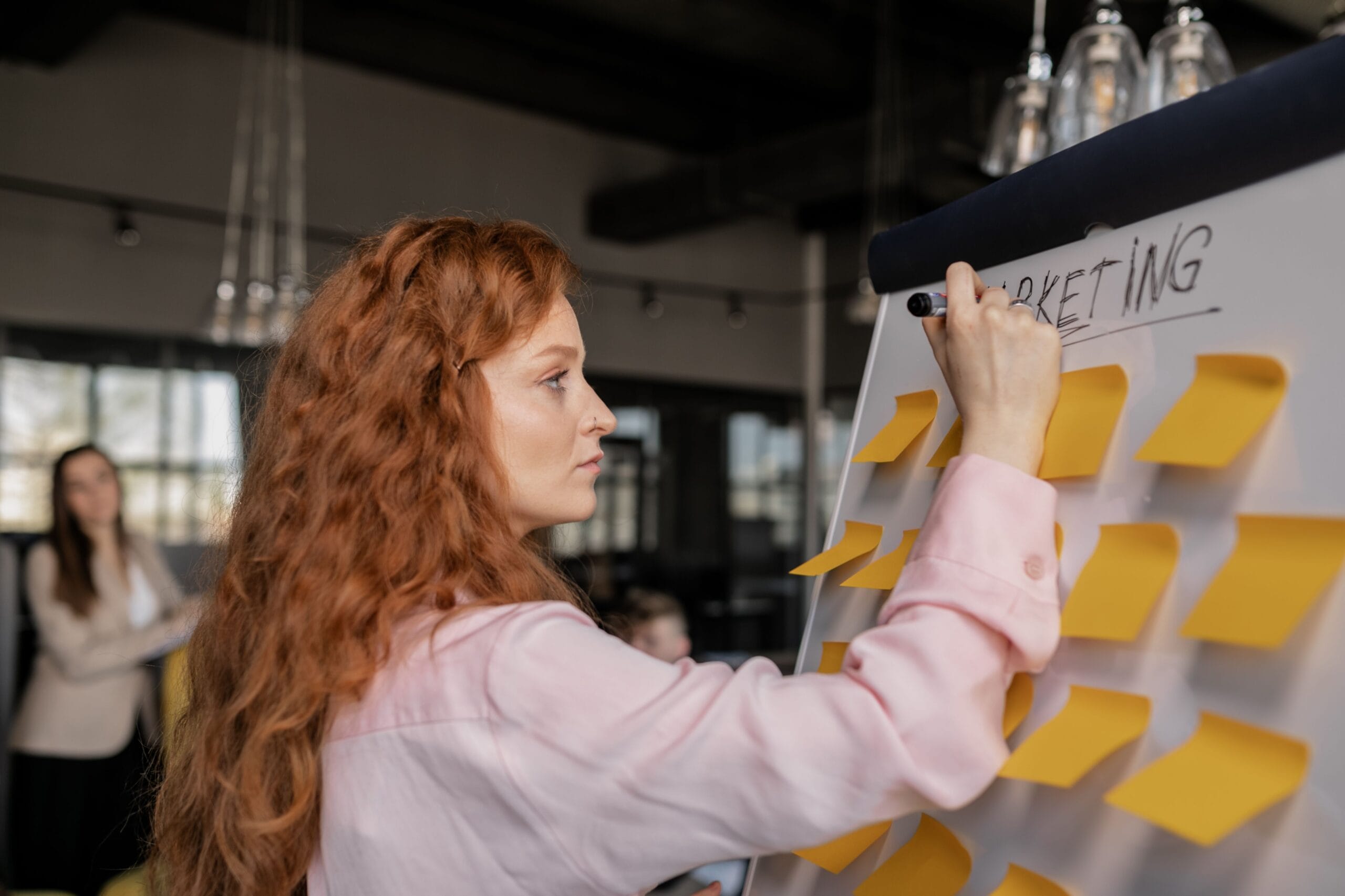 Cheffe de projet marketing préparant son brief sur un tableau blanc avec des post-it