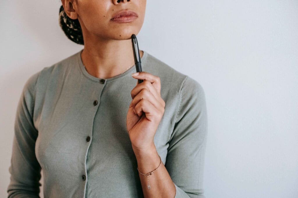 Femme pensive debout qui tient un stylo