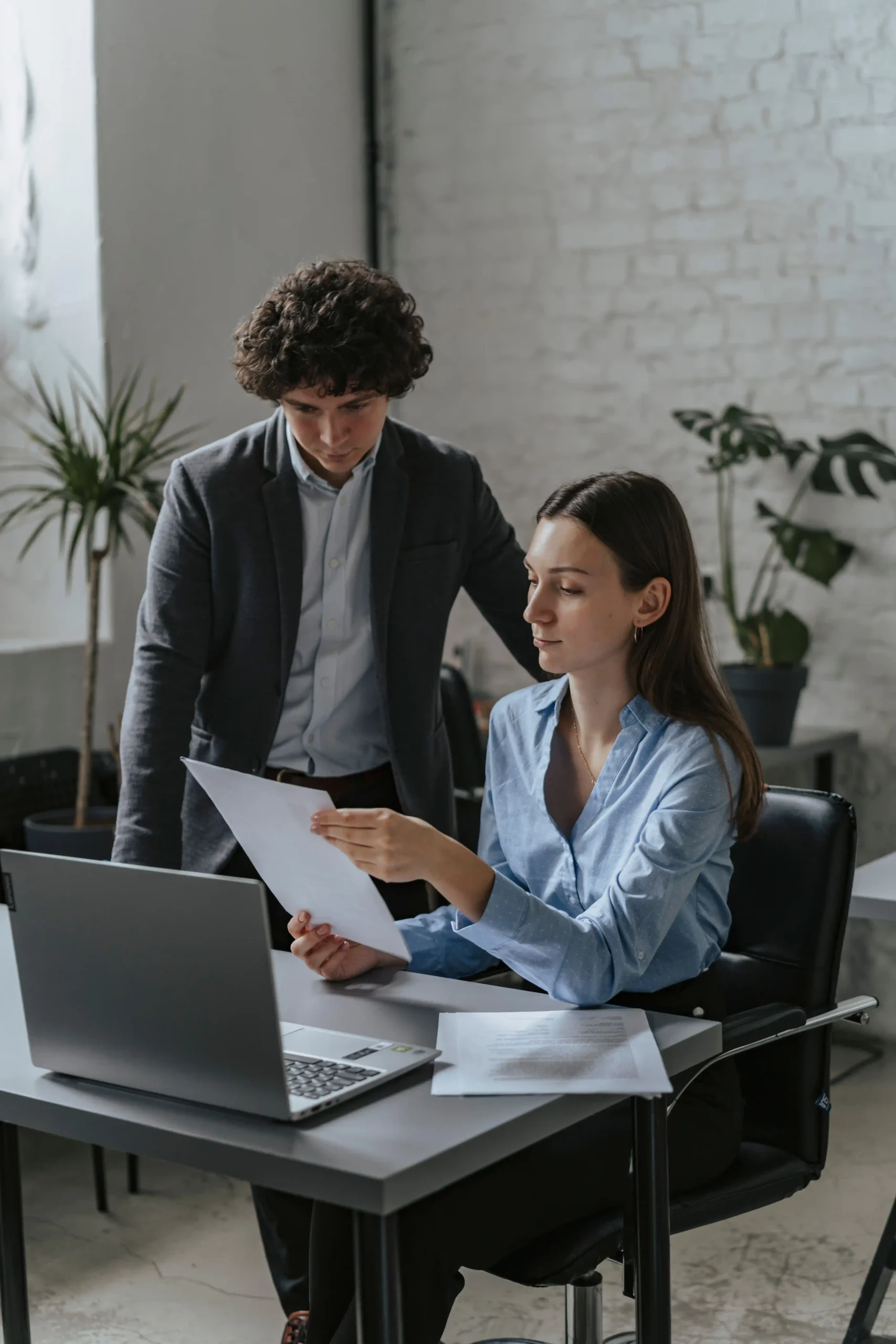 Deux professionnels dans un bureau examinant des documents sur un ordinateur portable