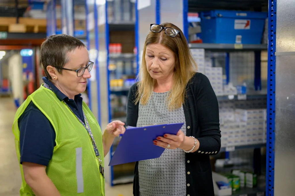 Manager retail et son employé de vente dans un entrepôt examinant une liste de contrôle d'inventaire