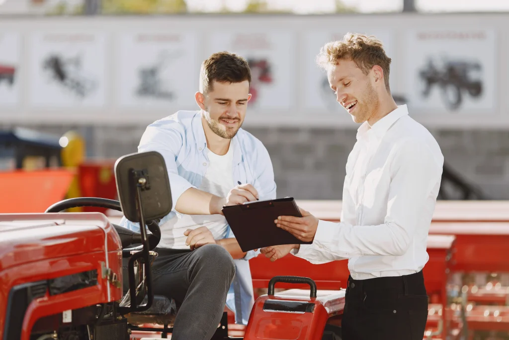 Commercial et son client discutant de l'achat d'un tracteur, collaborant en extérieur